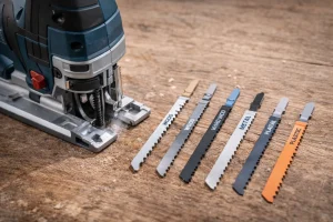 Scie sauteuse accompagnée de différentes lames pour le bois, le métal et le plastique, disposées sur un plan de travail